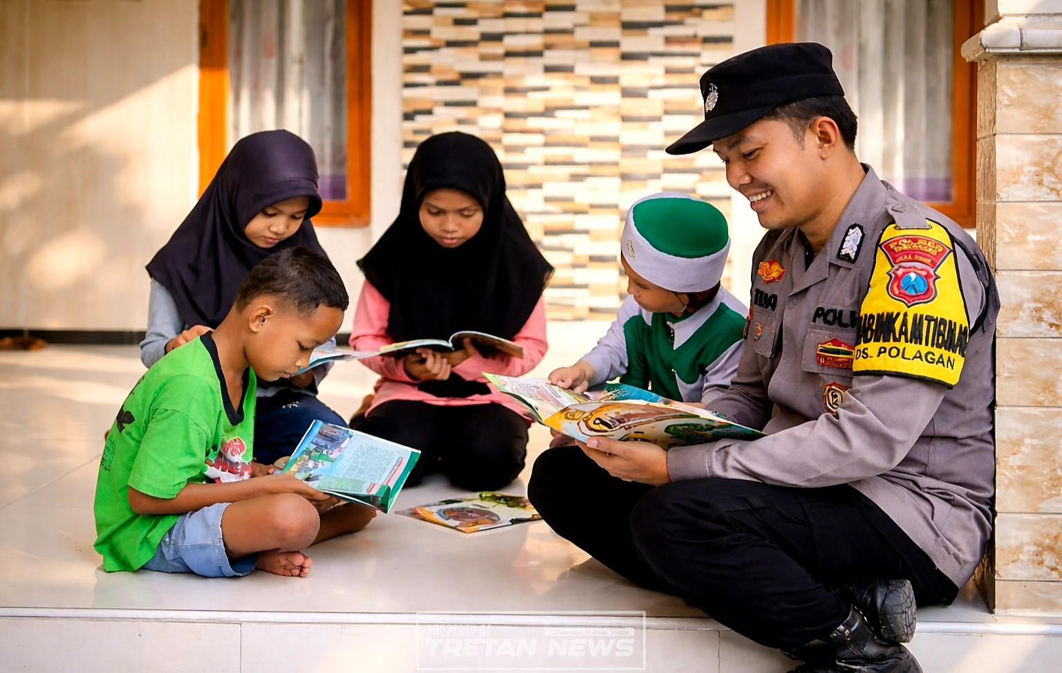 Bhabinkamtibmas Polres Pamekasan membaca buku bersama anak-anak dalam program Motor Pintar untuk meningkatkan minat baca di lingkungan masyarakat
