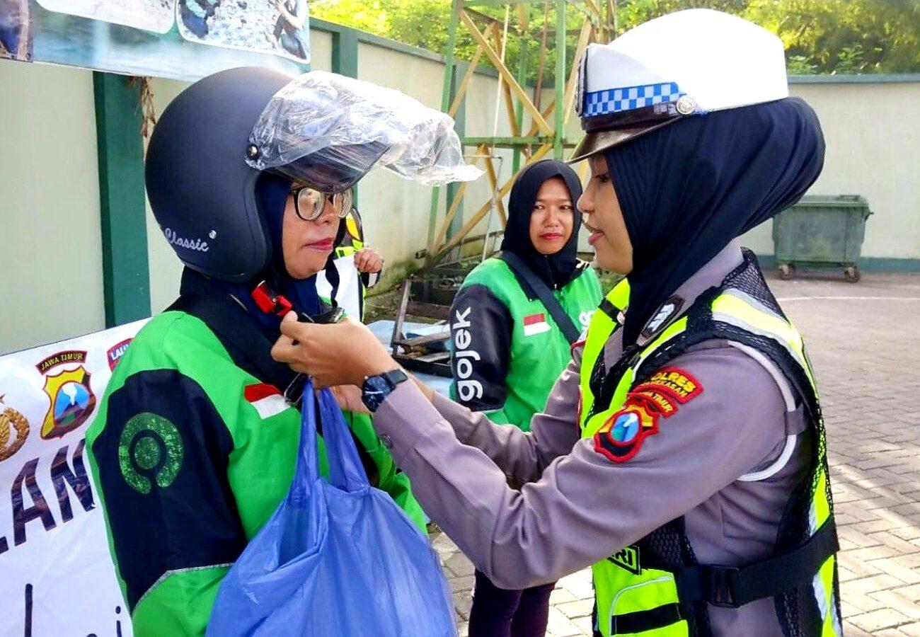 Polwan Satlantas Polres Pamekasan memasangkan helm kepada pengemudi ojol perempuan dalam edukasi safety riding pada Hari Kartini 2026 di Pamekasan