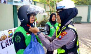 Polwan Satlantas Polres Pamekasan memasangkan helm kepada pengemudi ojol perempuan dalam edukasi safety riding pada Hari Kartini 2026 di Pamekasan