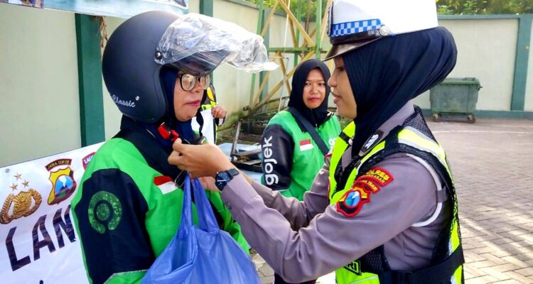 Polwan Satlantas Polres Pamekasan memasangkan helm kepada pengemudi ojol perempuan dalam edukasi safety riding pada Hari Kartini 2026 di Pamekasan
