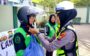 Polwan Satlantas Polres Pamekasan memasangkan helm kepada pengemudi ojol perempuan dalam edukasi safety riding pada Hari Kartini 2026 di Pamekasan