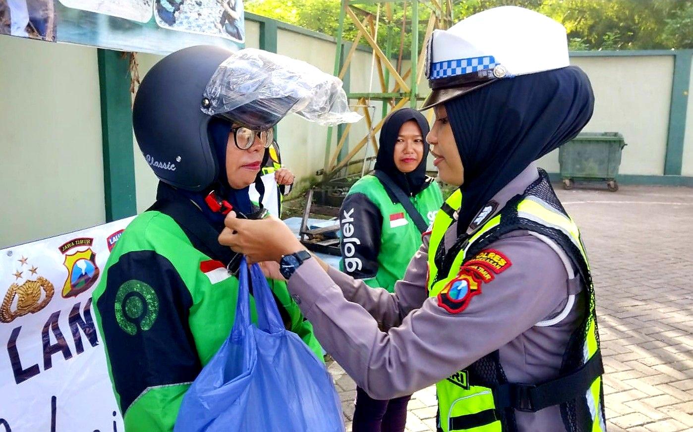 Polwan Satlantas Polres Pamekasan memasangkan helm kepada pengemudi ojol perempuan dalam edukasi safety riding pada Hari Kartini 2026 di Pamekasan